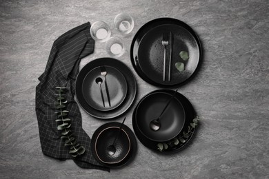 Photo of Stylish table setting. Dishes, cutlery, glasses and eucalyptus branches on grey surface, flat lay