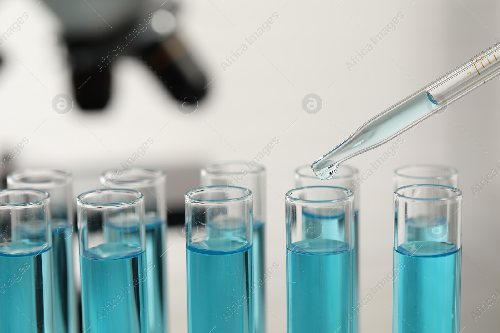 Photo of Dripping liquid from pipette into test tube in laboratory, closeup