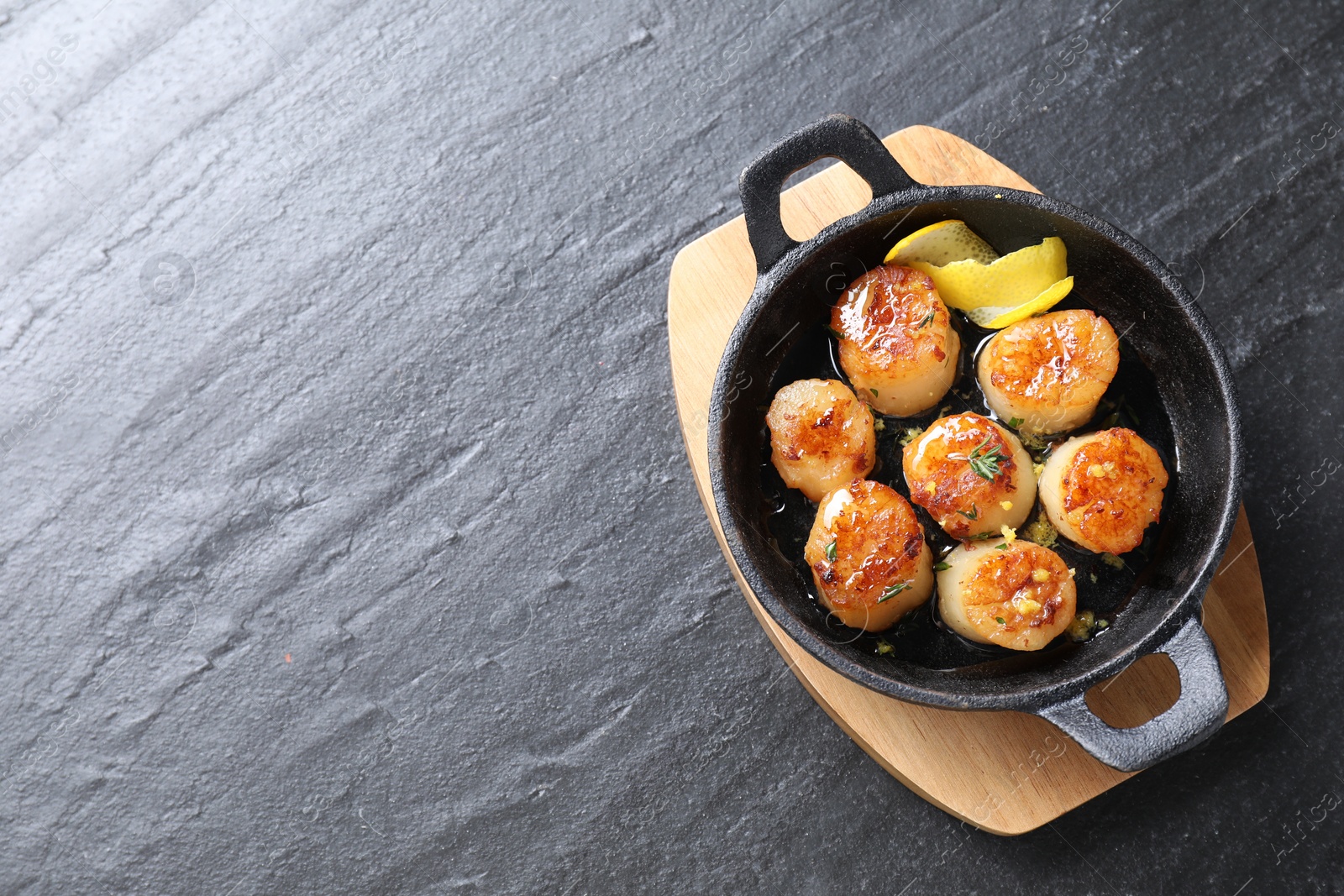 Photo of Delicious fried scallops on dark gray textured table, top view. Space for text