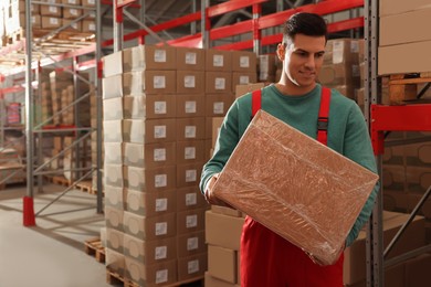 Worker with cardboard box in warehouse, space for text. Wholesaling