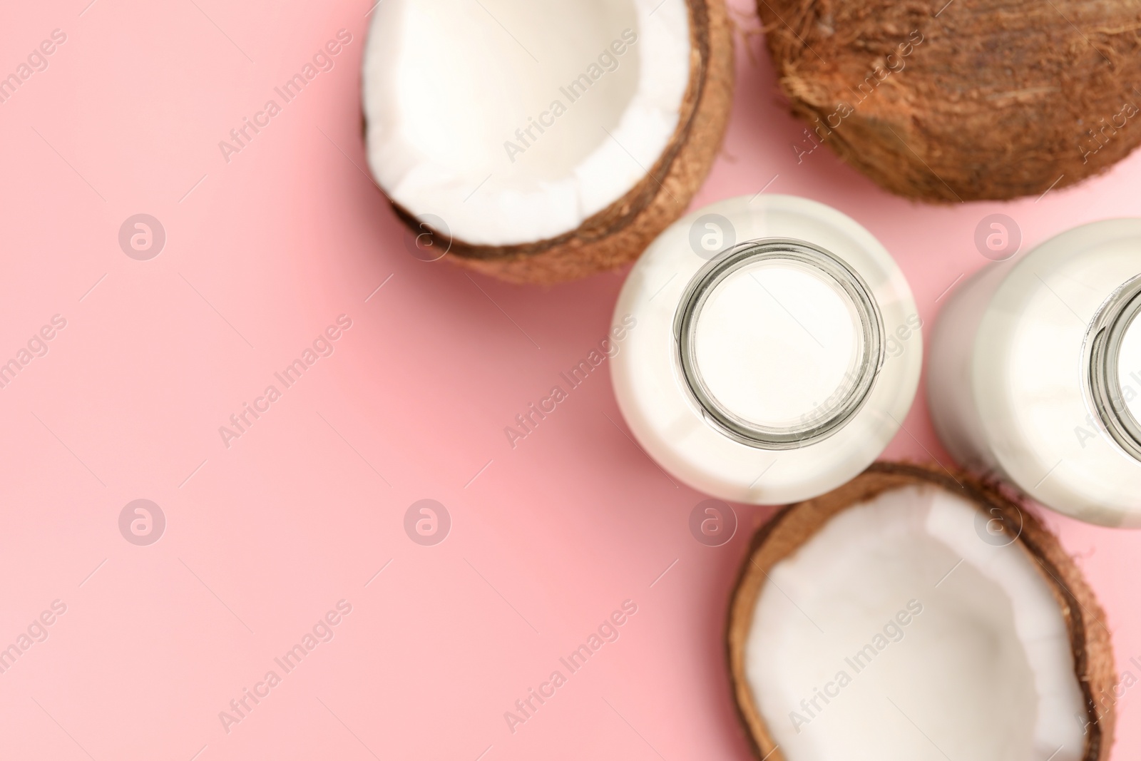 Photo of Delicious vegan milk and coconuts on pink background, flat lay. Space for text