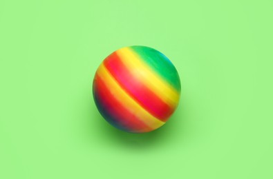 Bright rubber kids' ball on light green background, top view