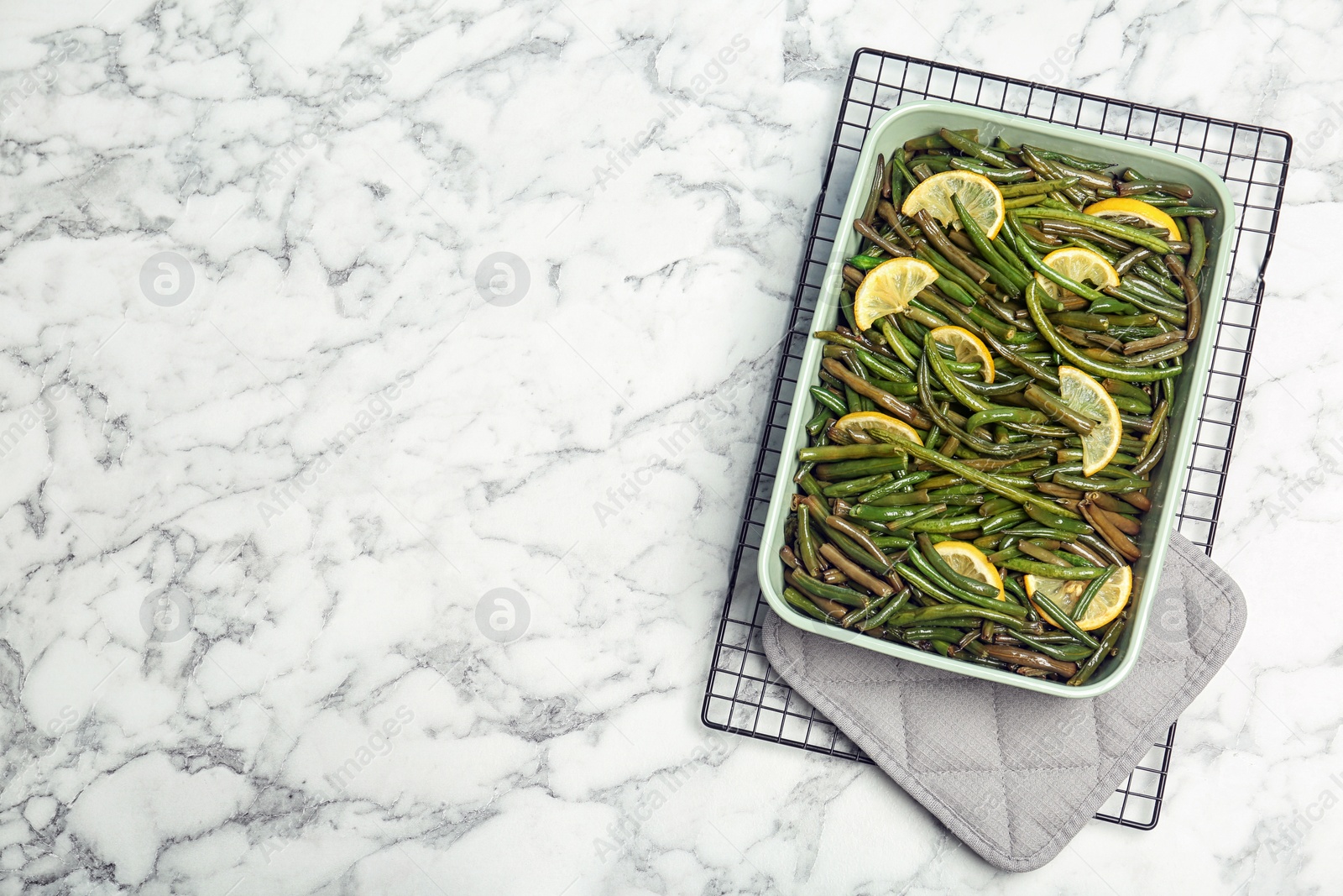 Photo of Dish with tasty green beans and lemons on marble table, top view