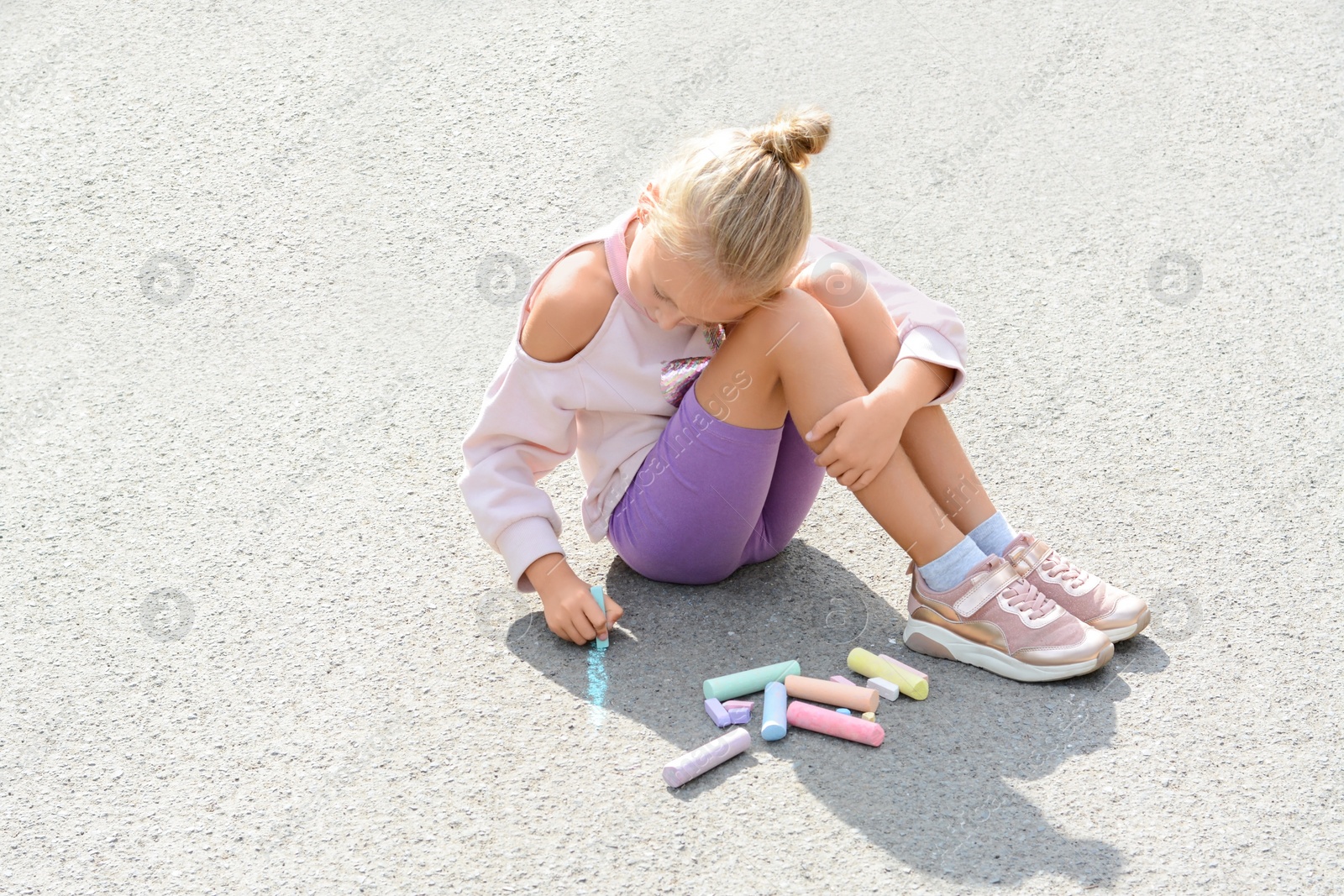 Photo of Little child drawing flower with chalk on asphalt