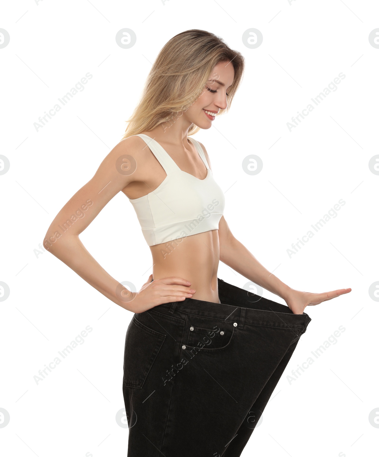 Photo of Young woman wearing big jeans after weight loss on white background