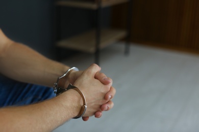 Man detained in handcuffs indoors, closeup view. Criminal law