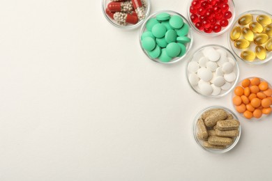 Photo of Different dietary supplements in bowls on white background, flat lay. Space for text