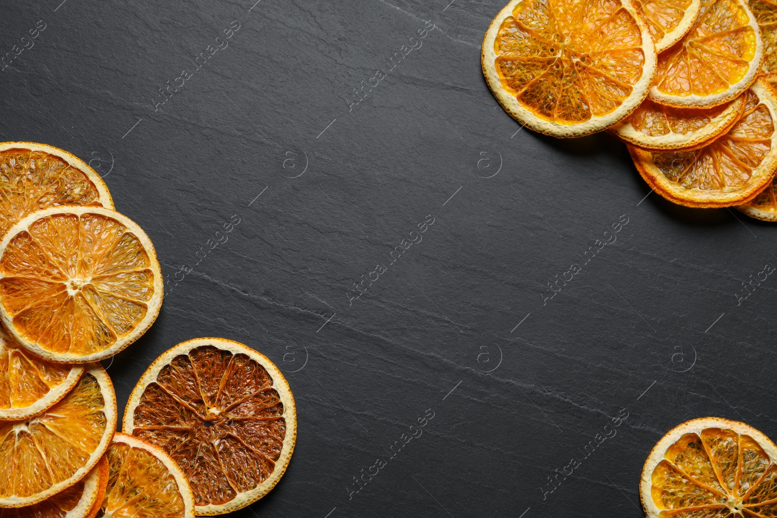 Photo of Many dry orange slices on black textured table, flat lay. Space for text