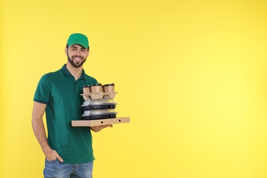 Photo of Young courier with different orders on color background, space for text. Food delivery service