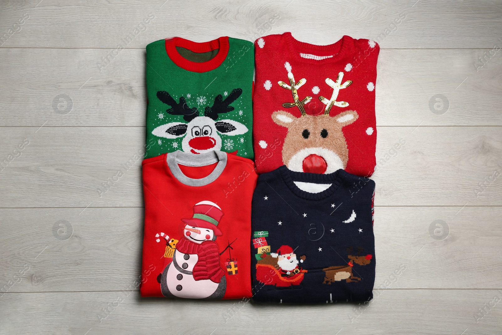 Photo of Folded warm Christmas sweaters on wooden table, flat lay