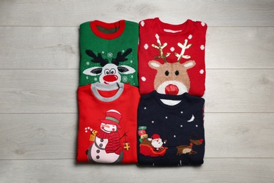 Photo of Folded warm Christmas sweaters on wooden table, flat lay