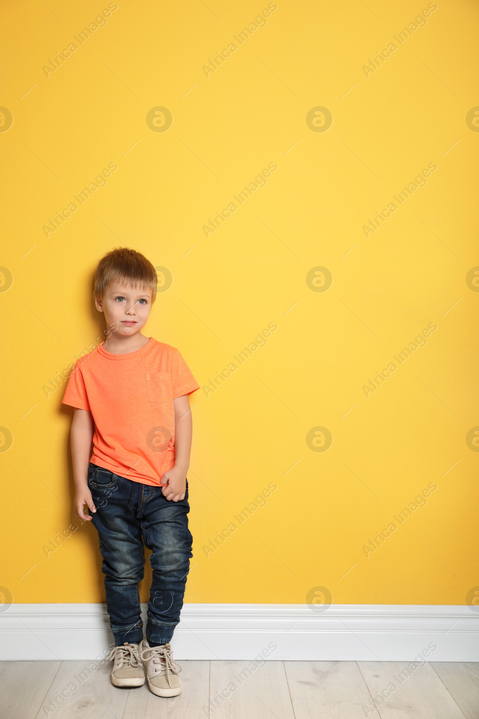 Photo of Portrait of cute little boy against color wall with space for text