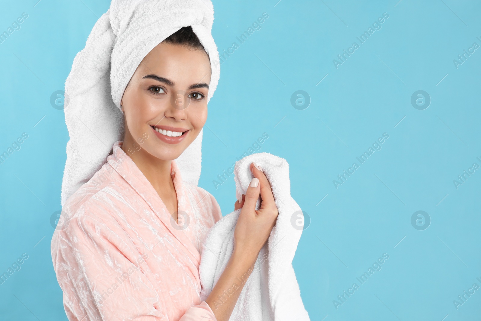 Photo of Young woman wiping hands with towel on light blue background