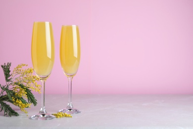 Glasses of Mimosa cocktail on light table. Space for text