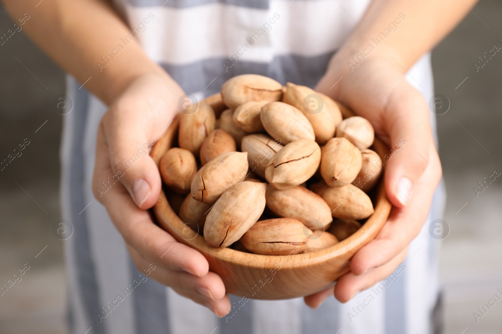 Photo of Woman holding bowl with pecan nuts in hands, closeup