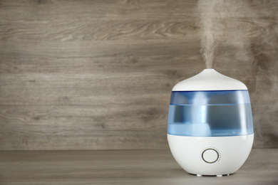 Modern air humidifier on wooden table. Space for text