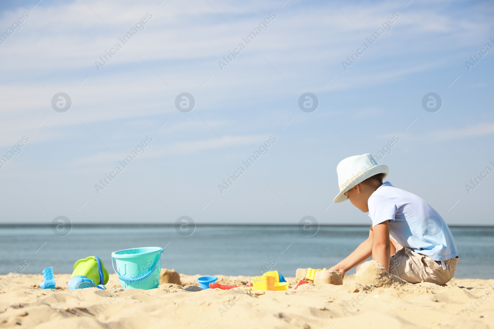 Photo of Cute little boy playing with plastic toys on sandy beach