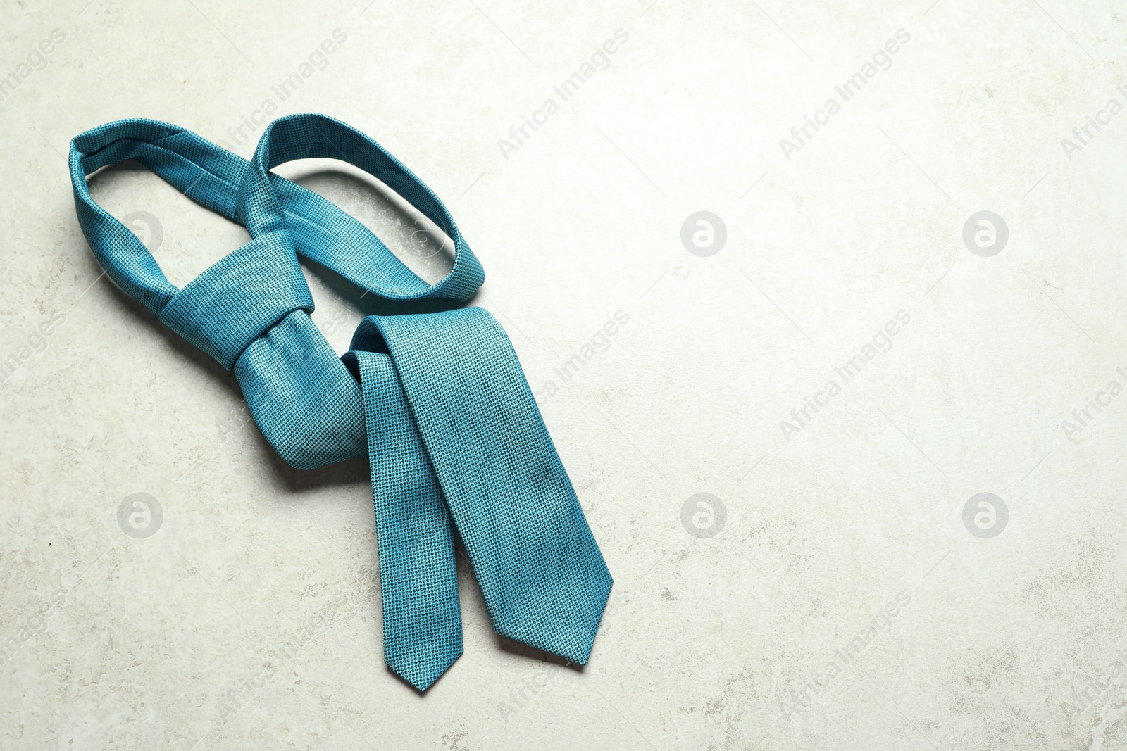 Photo of One blue necktie on light textured table, top view. Space for text