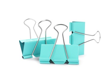 Photo of Turquoise binder clips on white background. Stationery