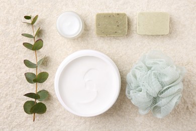 Photo of Flat lay composition with moisturizing cream in open jar and other body care products on light textured table