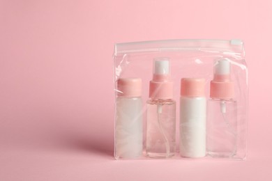 Photo of Cosmetic travel kit in plastic bag on pink background. Space for text