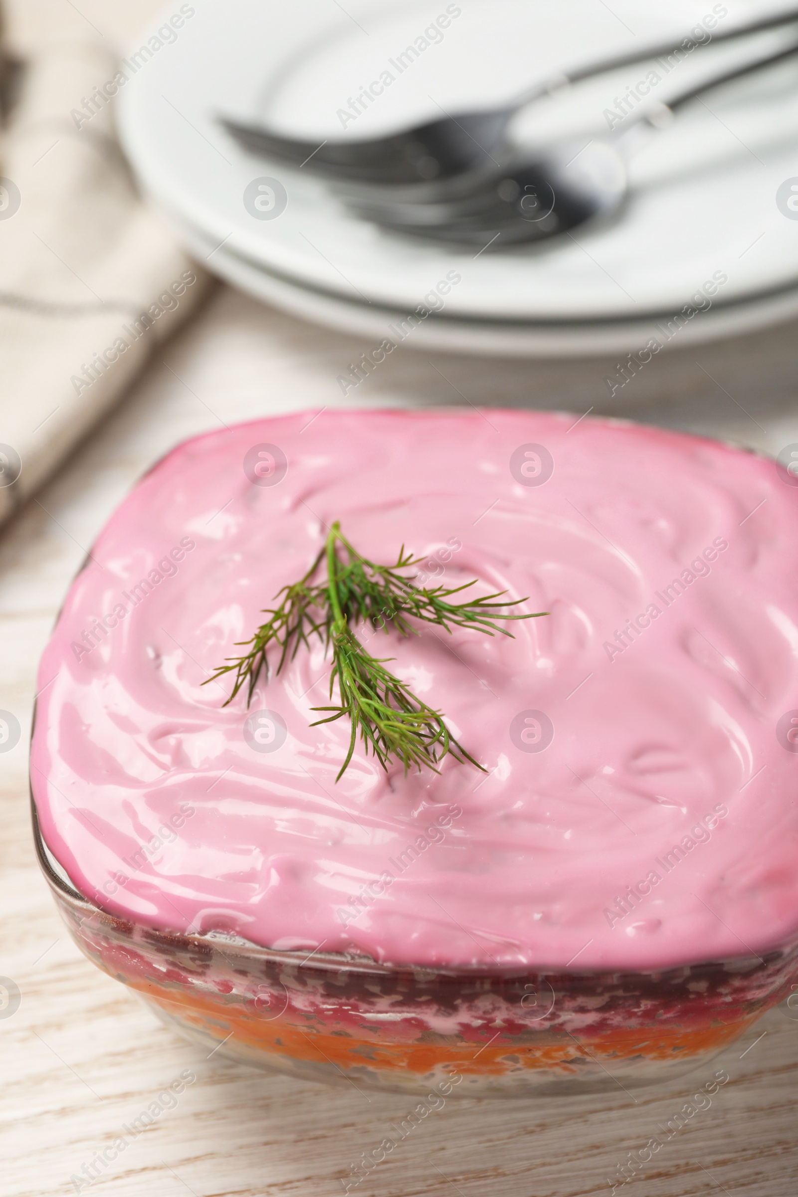 Photo of Herring under fur coat salad on white wooden table, closeup. Traditional Russian dish