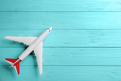 Toy airplane on light blue wooden background, top view. Space for text