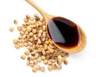 Photo of Tasty soy sauce in spoon and soybeans isolated on white, top view