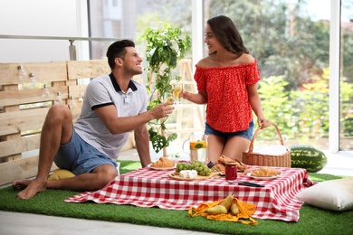 Happy couple with refreshing drink imitating picnic at home