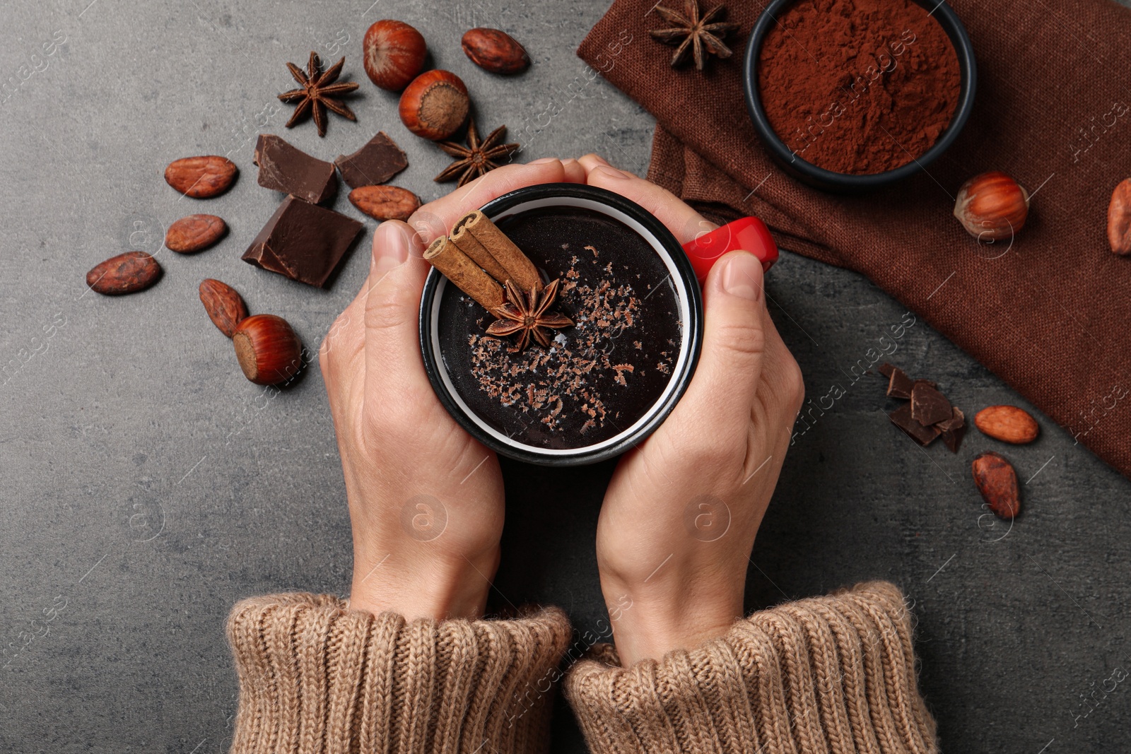 Photo of Woman with mug of yummy hot chocolate at grey table, top view