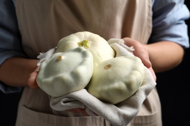Photo of Woman with fresh ripe pattypan squashes on black background, closeup