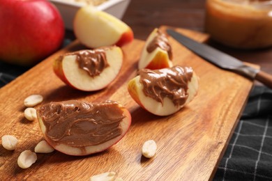 Photo of Slices of fresh apple with nut butter and peanuts on wooden board