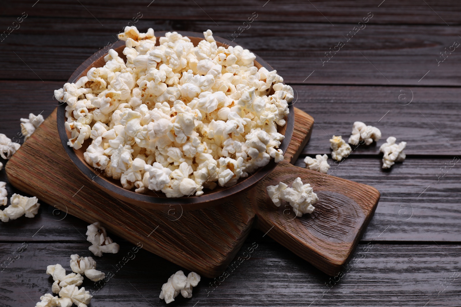 Photo of Tasty popcorn on black wooden table, closeup