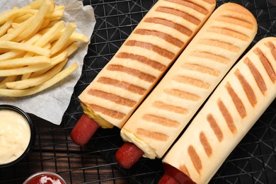 Delicious french hot dogs, fries and dip sauces on wooden table, top view