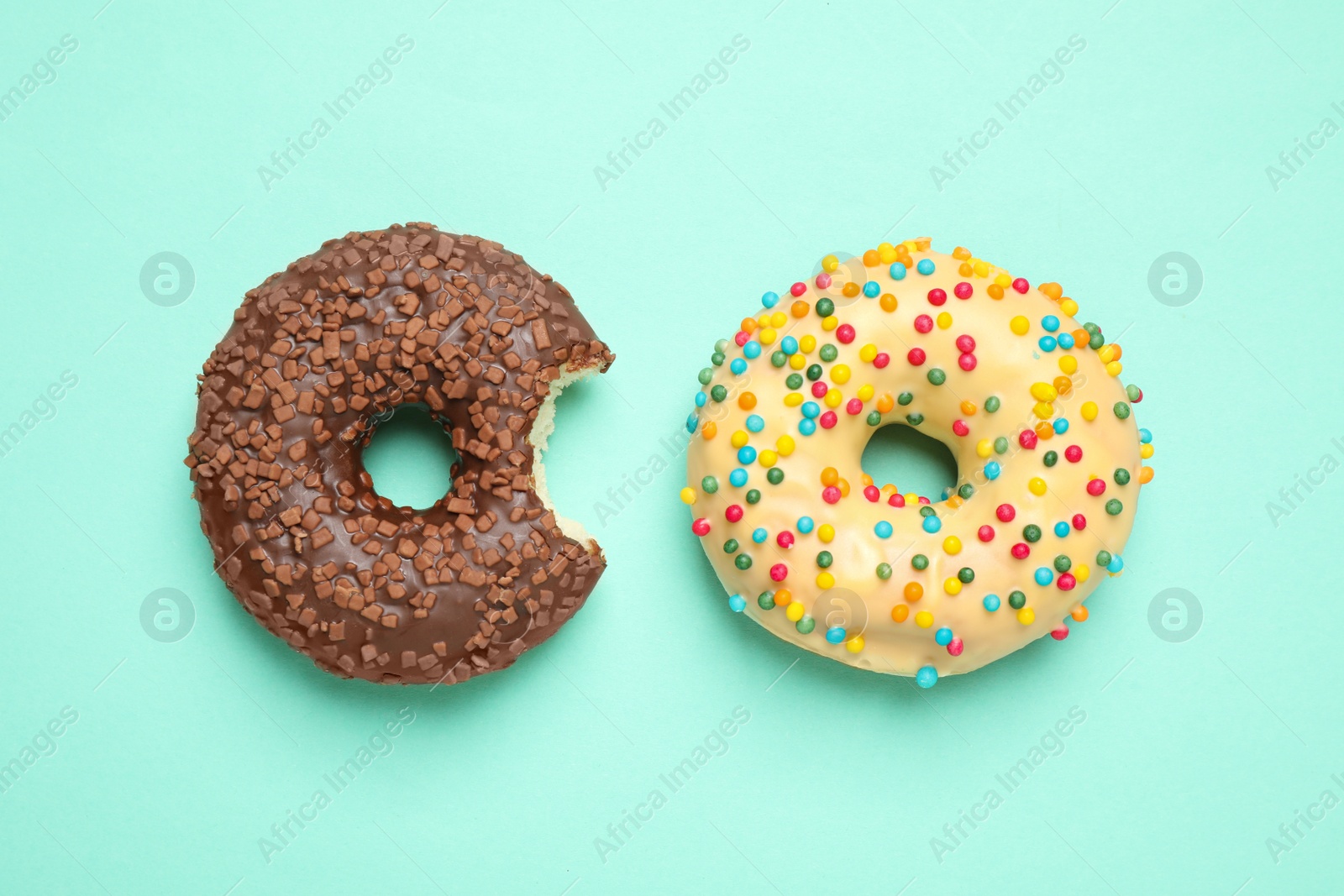 Photo of Delicious glazed donuts on turquoise background, flat lay