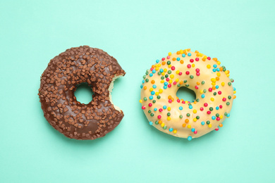 Photo of Delicious glazed donuts on turquoise background, flat lay