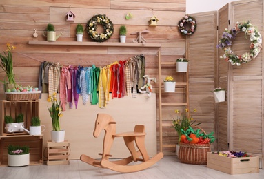 Photo of Stylish Easter photo zone with flower wreaths, rocking horse and houseplants