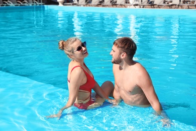 Happy young couple relaxing in swimming pool at resort