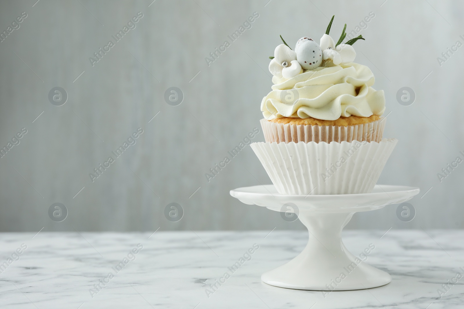 Photo of Tasty Easter cupcake with vanilla cream on white marble table, space for text