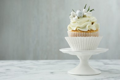 Photo of Tasty Easter cupcake with vanilla cream on white marble table, space for text