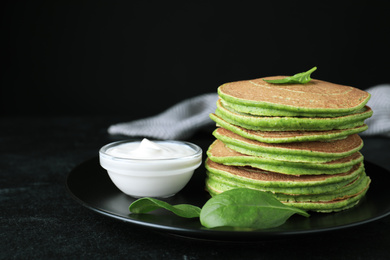 Photo of Tasty spinach pancakes on black table, closeup