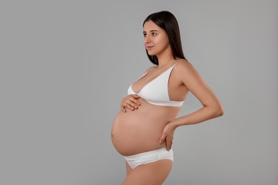Photo of Beautiful pregnant woman in stylish comfortable underwear on grey background, space for text
