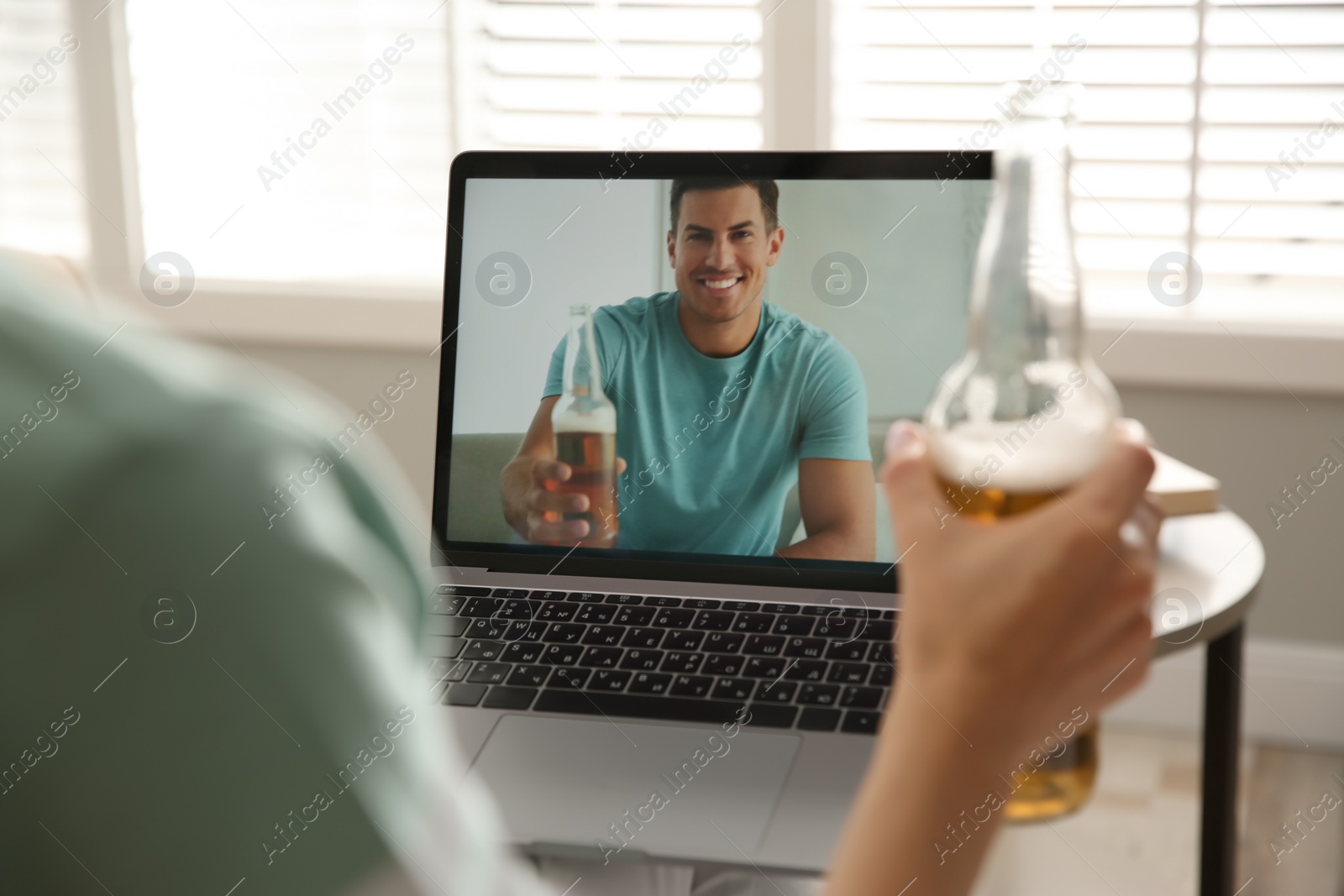 Photo of Friends drinking beer while communicating through online video conference at home. Social distancing during coronavirus pandemic