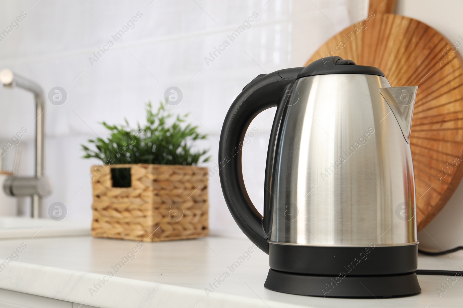 Photo of Modern electric kettle on counter in kitchen. Space for text