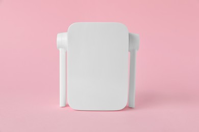 New modern Wi-Fi repeater on pink background