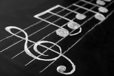 Music scale with treble clef and notes on chalkboard, closeup