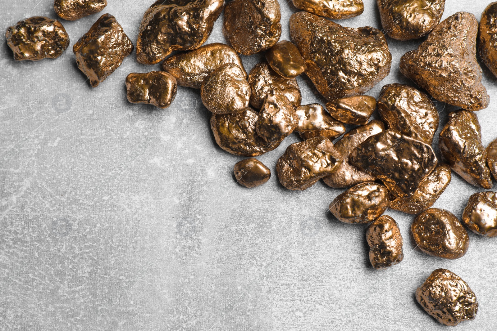 Photo of Pile of gold nuggets on light grey table, flat lay. Space for text