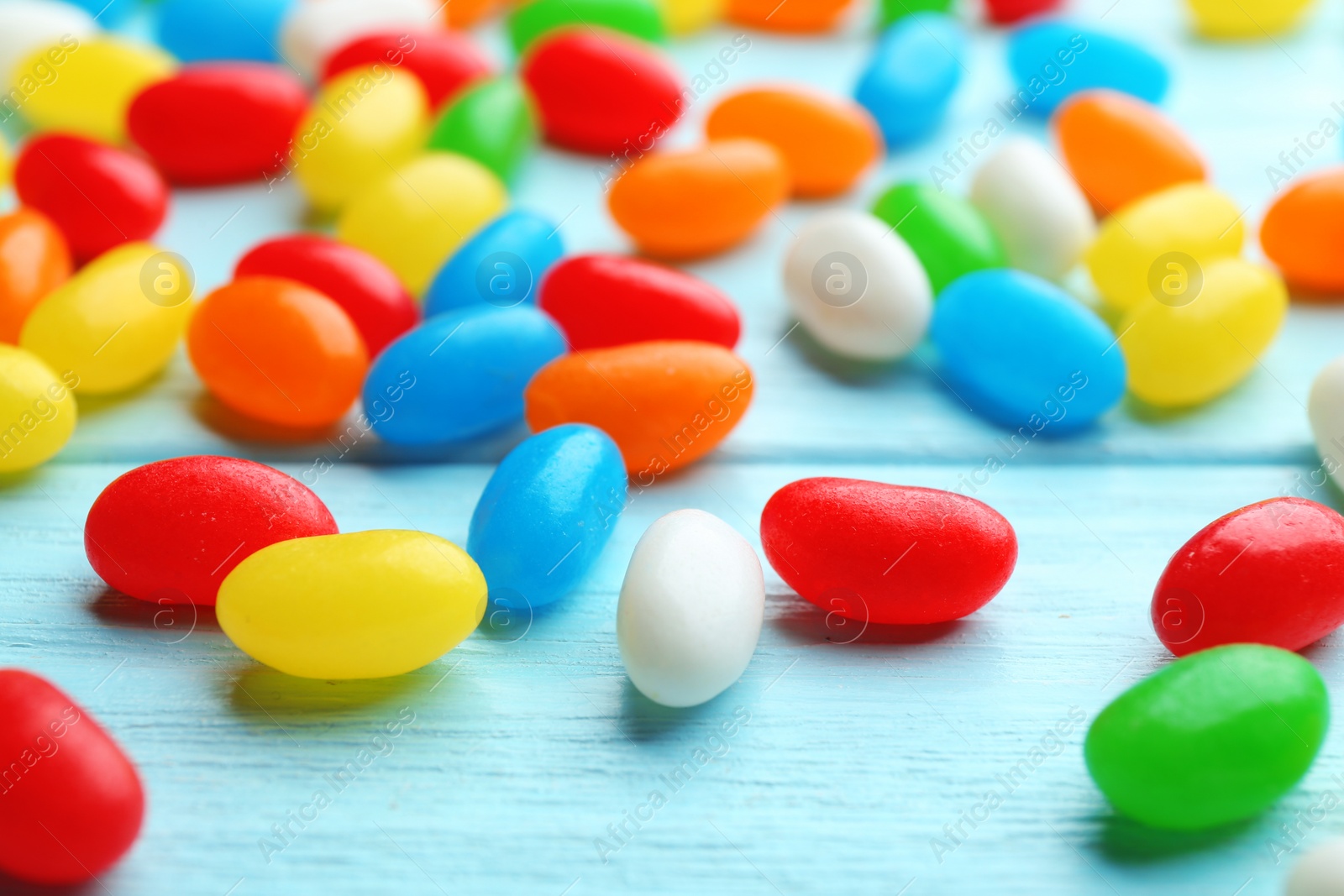Photo of Colorful jelly beans on light blue wooden background, closeup