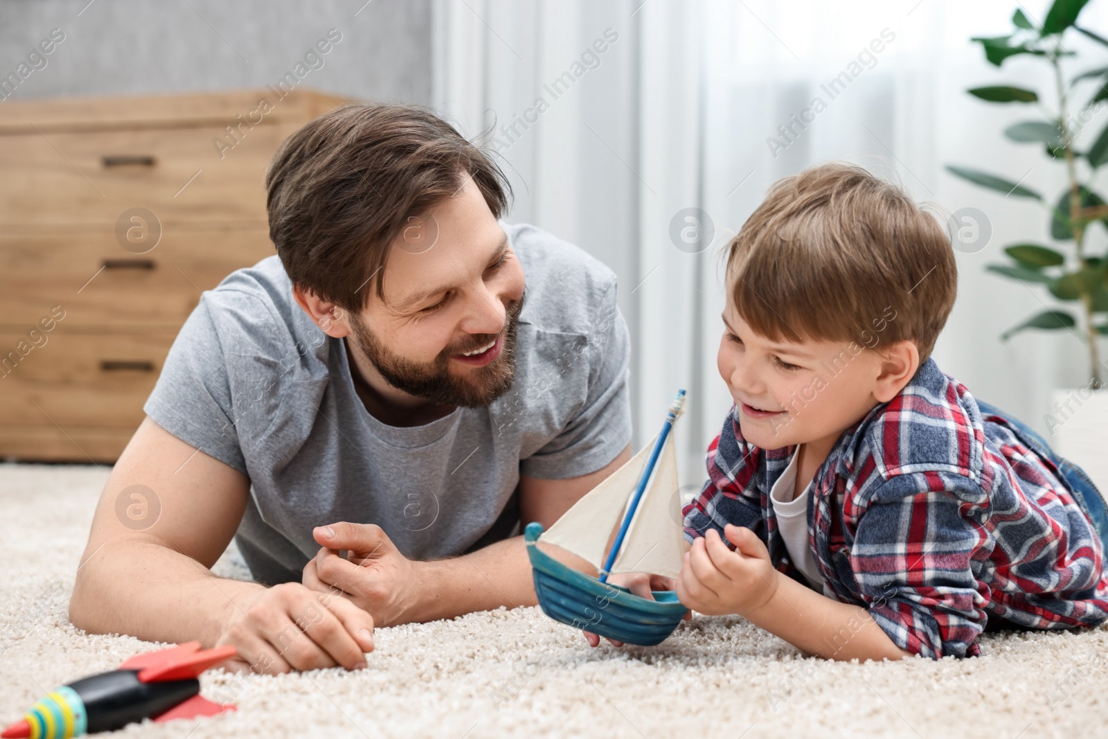 Photo of Happy dad and son playing toys together at home