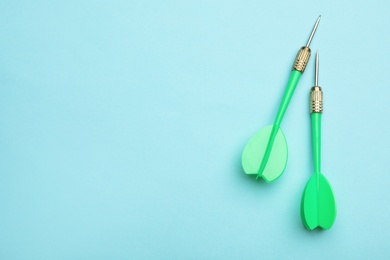 Photo of Green dart arrows on blue background, flat lay with space for text